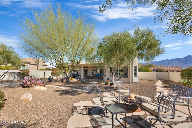 rear view of house with a mountain view, a fire pit, and a patio