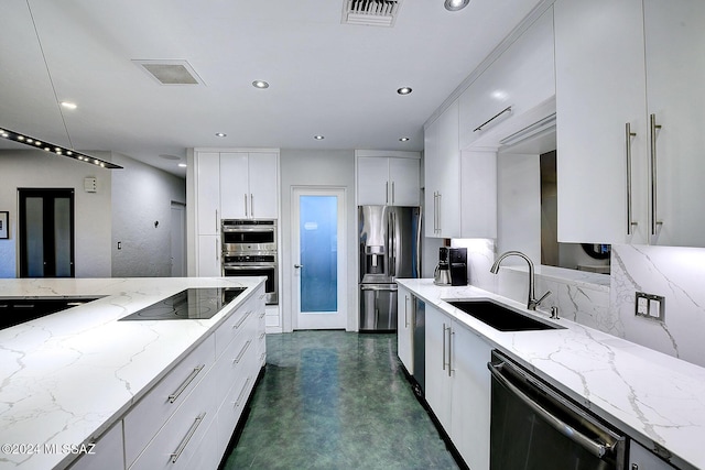 kitchen with sink, white cabinetry, stainless steel appliances, light stone countertops, and backsplash