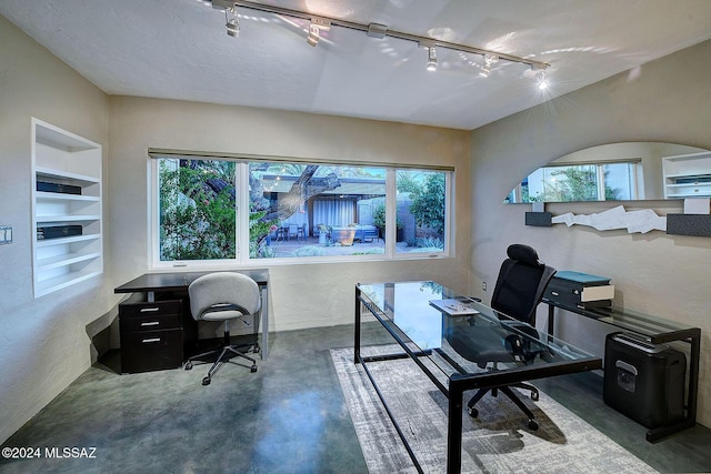 office area featuring built in shelves, a textured ceiling, and a healthy amount of sunlight