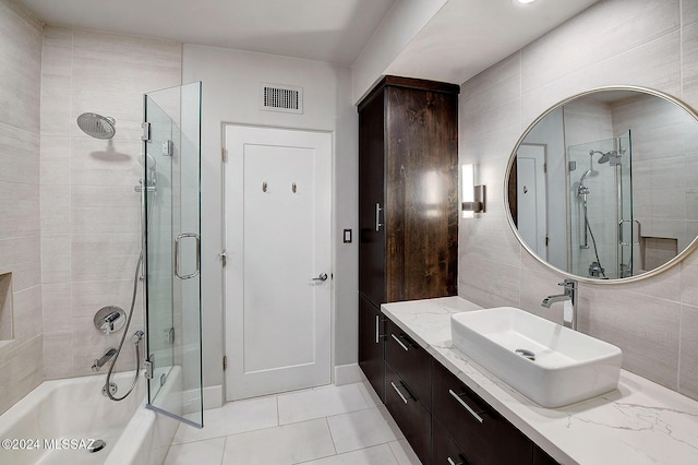 bathroom with enclosed tub / shower combo, tile patterned flooring, tile walls, vanity, and decorative backsplash