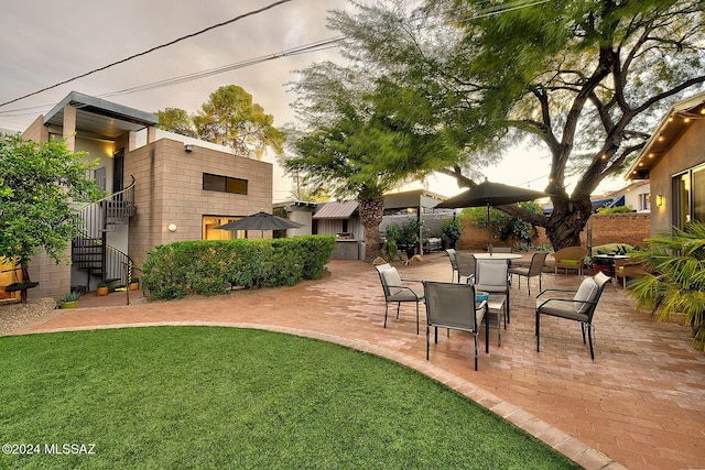 patio terrace at dusk featuring a lawn