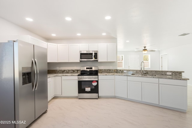 kitchen with sink, ceiling fan, stainless steel appliances, light stone countertops, and white cabinets