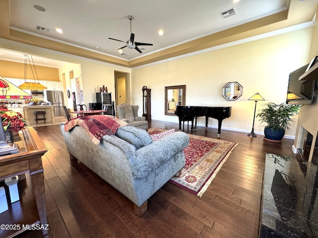 living area with dark wood-style floors, a raised ceiling, visible vents, and baseboards