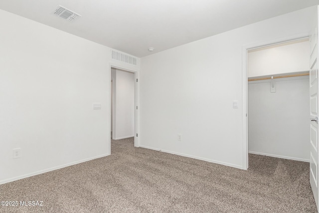 unfurnished bedroom featuring carpet, a spacious closet, and a closet