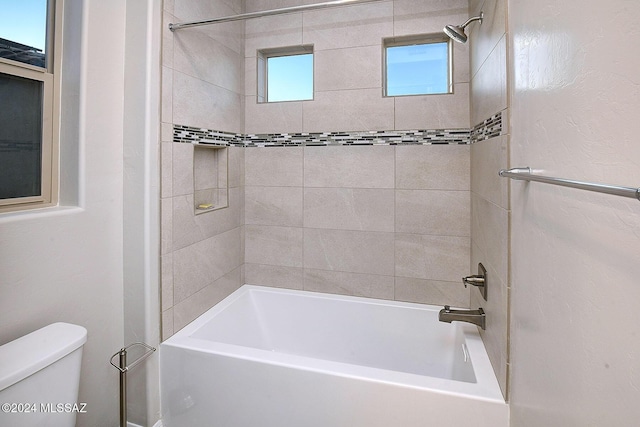 bathroom featuring tiled shower / bath and toilet