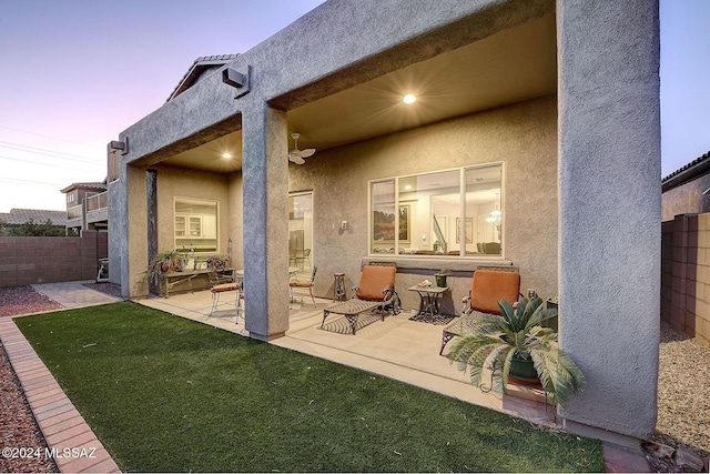 back house at dusk featuring a patio and a yard