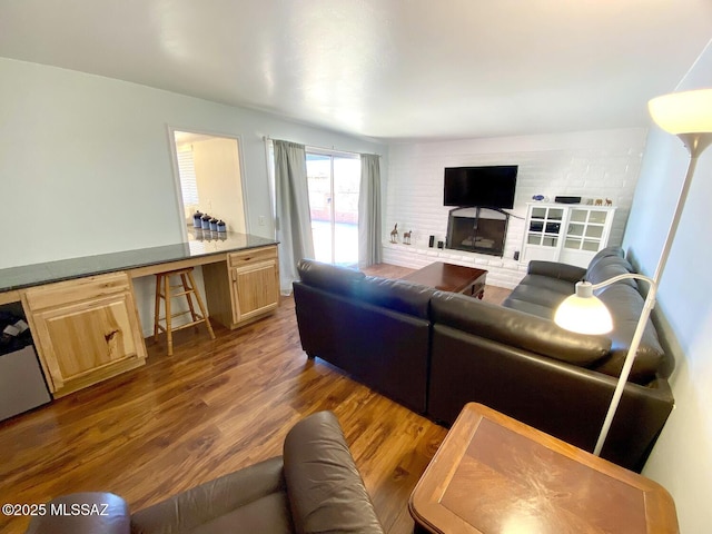 living room with a brick fireplace and dark hardwood / wood-style flooring