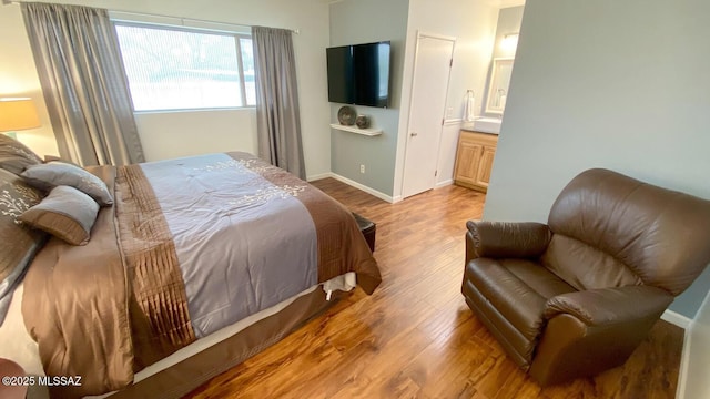 bedroom with light wood-type flooring and ensuite bath