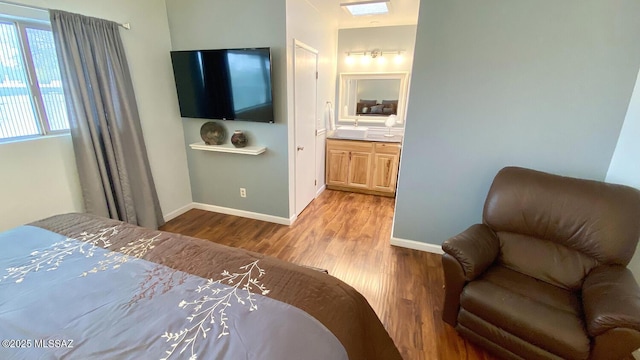 bedroom with ensuite bathroom and light hardwood / wood-style floors