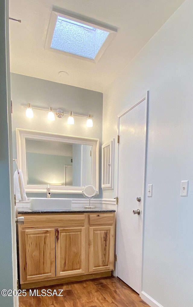 bathroom with vanity, a skylight, and hardwood / wood-style floors