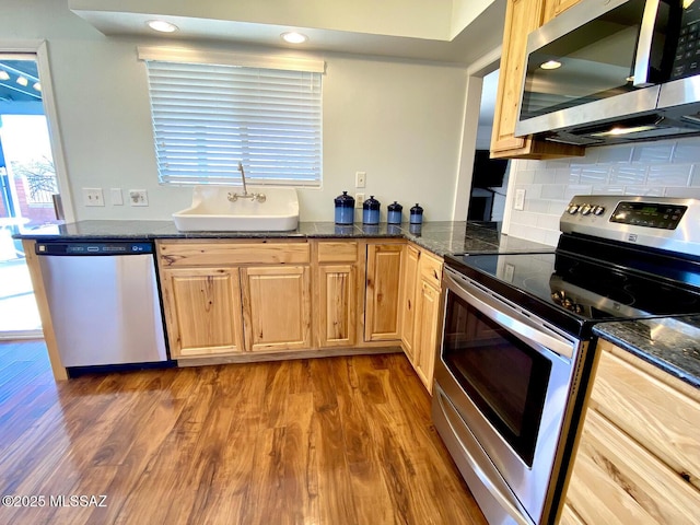 kitchen with dark wood-type flooring, appliances with stainless steel finishes, sink, and dark stone countertops