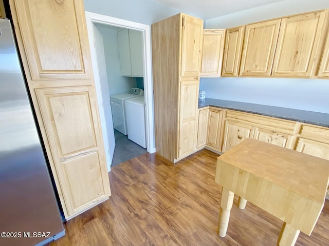 kitchen with washer and dryer, hardwood / wood-style flooring, stainless steel refrigerator, and light brown cabinetry