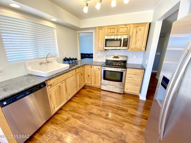 kitchen with sink, appliances with stainless steel finishes, tasteful backsplash, light hardwood / wood-style floors, and light brown cabinetry