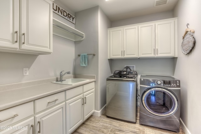 laundry room with independent washer and dryer, sink, light hardwood / wood-style flooring, and cabinets