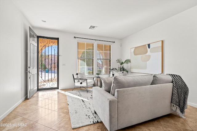 living room with light tile patterned floors, visible vents, and baseboards