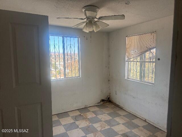 unfurnished room featuring a textured ceiling, light floors, and a ceiling fan