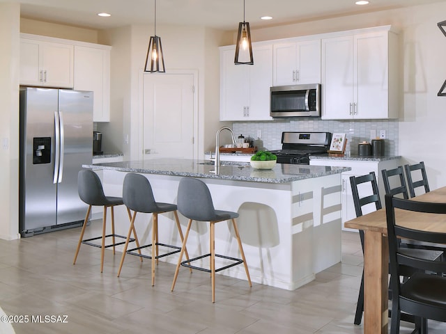 kitchen with white cabinetry, appliances with stainless steel finishes, sink, and a center island with sink