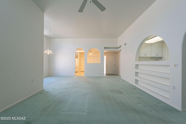 unfurnished room featuring light colored carpet, ceiling fan, and built in shelves