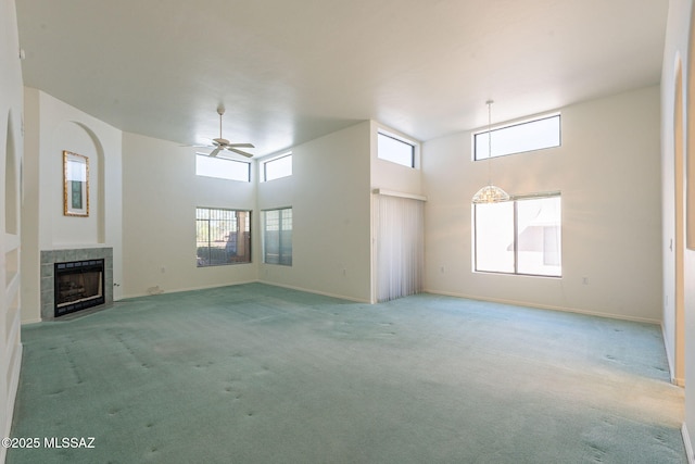 unfurnished living room featuring ceiling fan, carpet, a tile fireplace, and a high ceiling