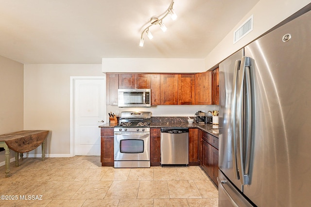 kitchen with stainless steel appliances and dark stone counters