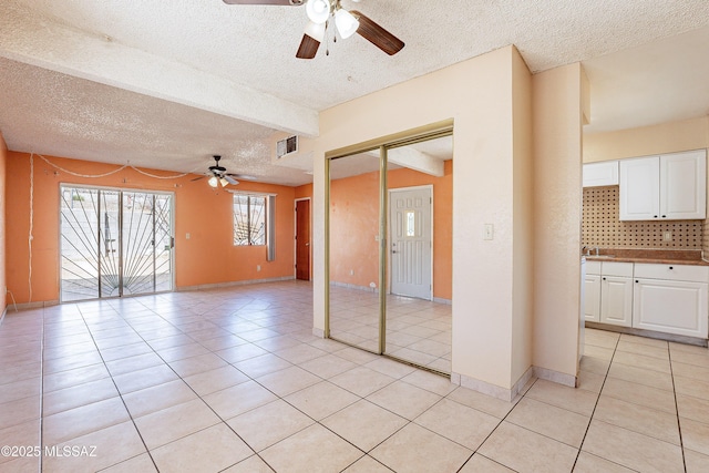 spare room with ceiling fan, light tile patterned floors, and a textured ceiling