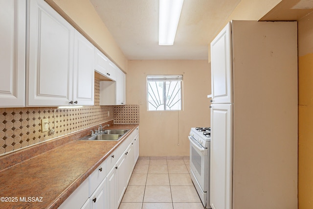 kitchen with light tile patterned flooring, sink, white cabinets, backsplash, and gas range gas stove