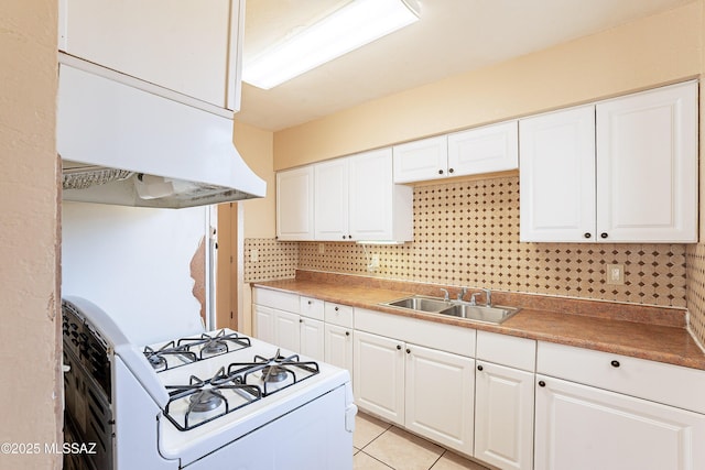 kitchen with sink, gas range gas stove, light tile patterned floors, backsplash, and white cabinets