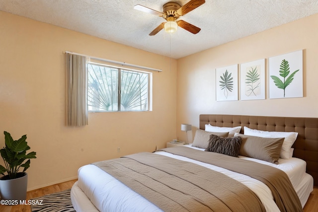 bedroom featuring ceiling fan, wood-type flooring, and a textured ceiling