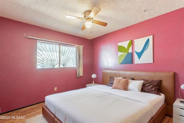 bedroom featuring ceiling fan, light hardwood / wood-style flooring, and a textured ceiling