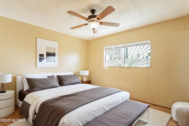 bedroom with hardwood / wood-style flooring, ceiling fan, and a textured ceiling