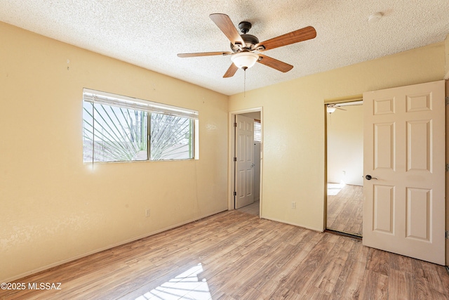 unfurnished bedroom featuring ceiling fan, a closet, light hardwood / wood-style flooring, and a textured ceiling