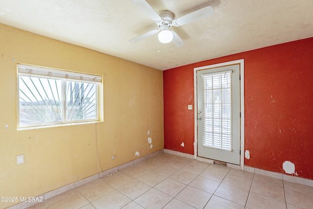 tiled empty room with ceiling fan and a textured ceiling