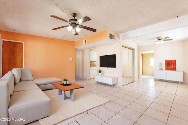 living room with ceiling fan, a textured ceiling, and light tile patterned floors