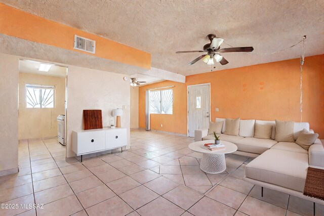 living room with light tile patterned floors, a textured ceiling, and ceiling fan