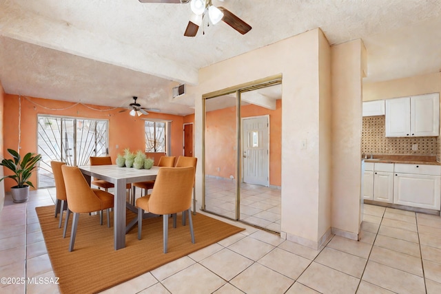 dining space with light tile patterned floors, beam ceiling, and a textured ceiling