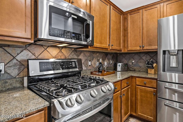 kitchen with light stone countertops, brown cabinets, and stainless steel appliances