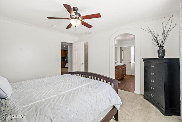 carpeted bedroom featuring arched walkways, ceiling fan, ornamental molding, and ensuite bathroom