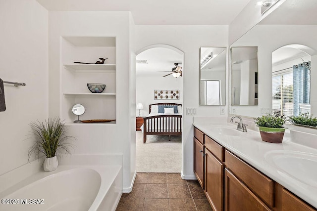 bathroom with a washtub, a sink, double vanity, ceiling fan, and ensuite bathroom