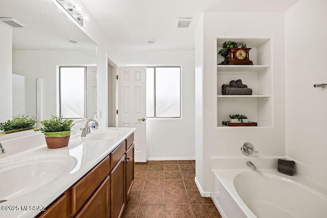 bathroom with a bath, double vanity, a sink, and visible vents