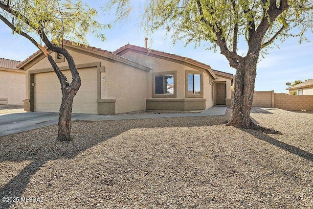 view of front of house with concrete driveway, a tile roof, stucco siding, fence, and a garage