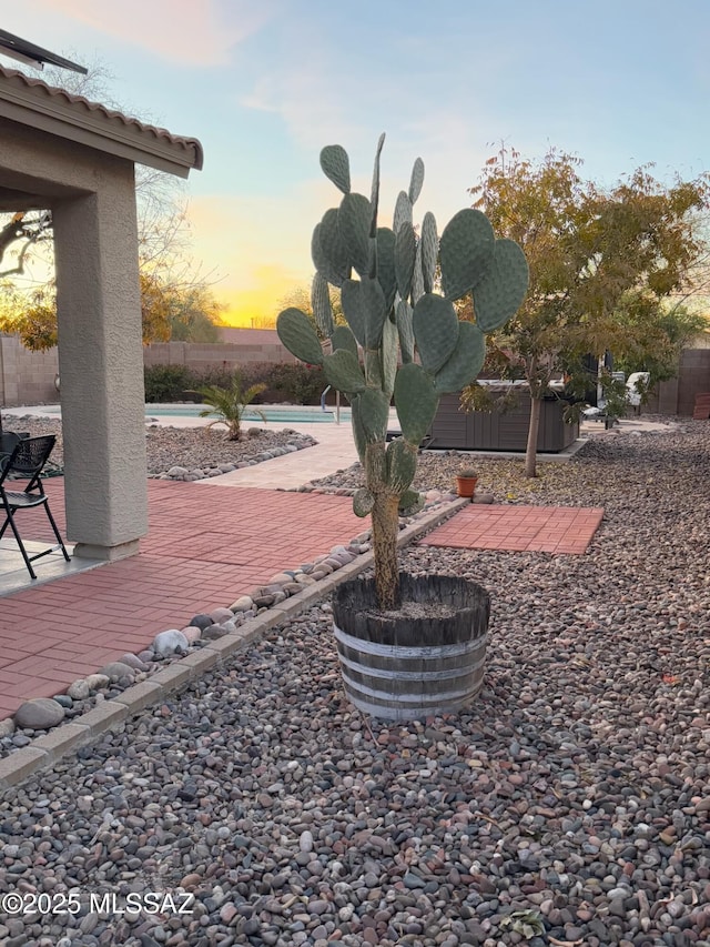 yard at dusk with a fenced in pool, a patio area, and a fenced backyard