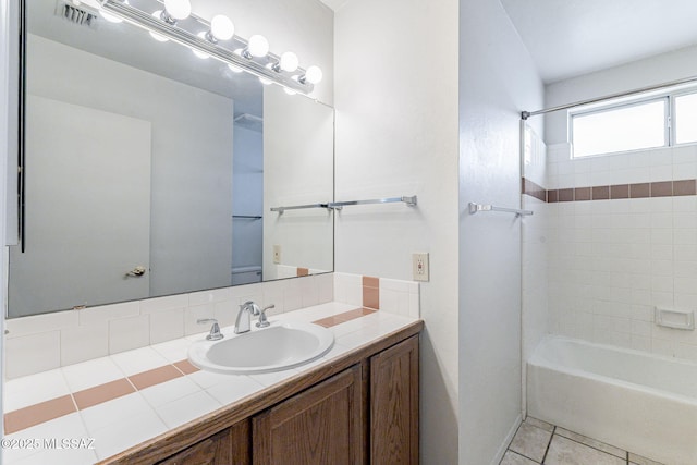 full bathroom with tile patterned flooring, tiled shower / bath, vanity, and toilet