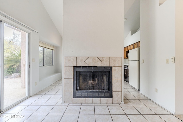 unfurnished living room with a tile fireplace, light tile patterned floors, and high vaulted ceiling