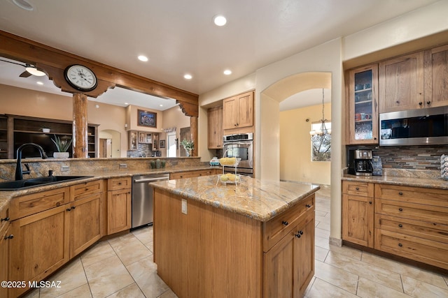 kitchen featuring a kitchen island, appliances with stainless steel finishes, sink, decorative backsplash, and light stone countertops