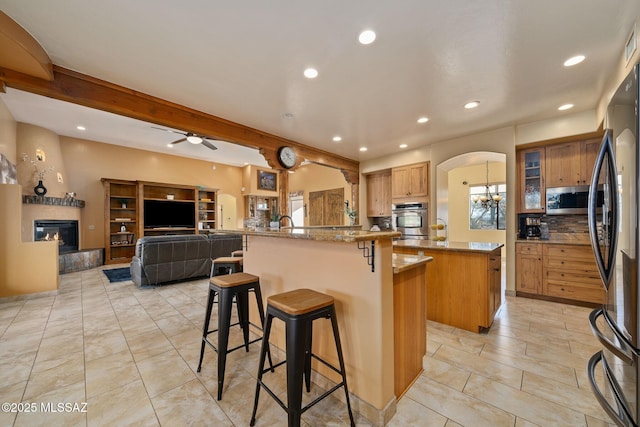 kitchen featuring a kitchen island, black refrigerator, beamed ceiling, a breakfast bar area, and kitchen peninsula