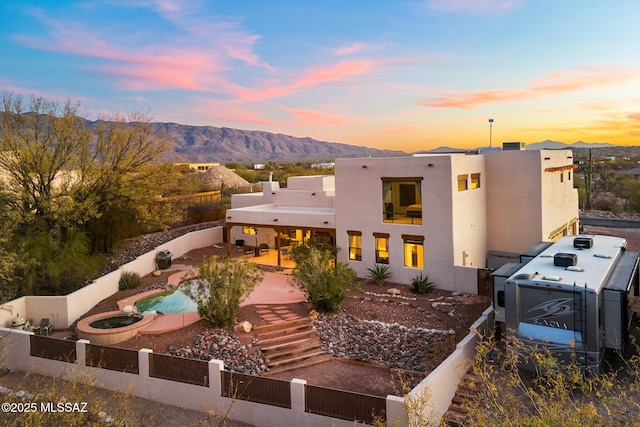 back house at dusk with a mountain view and a patio area