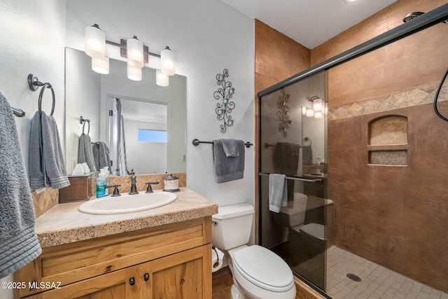 bathroom featuring vanity, a shower with shower door, and toilet