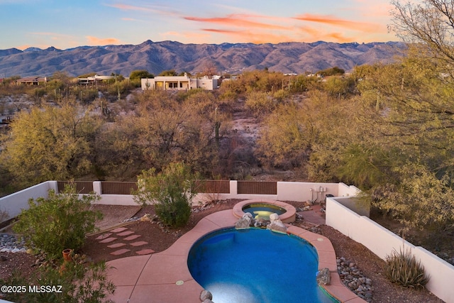 pool at dusk featuring an in ground hot tub and a mountain view