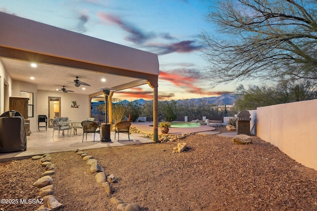 yard at dusk with a mountain view, a patio, and ceiling fan