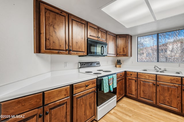 kitchen with white electric stove, sink, and light hardwood / wood-style floors